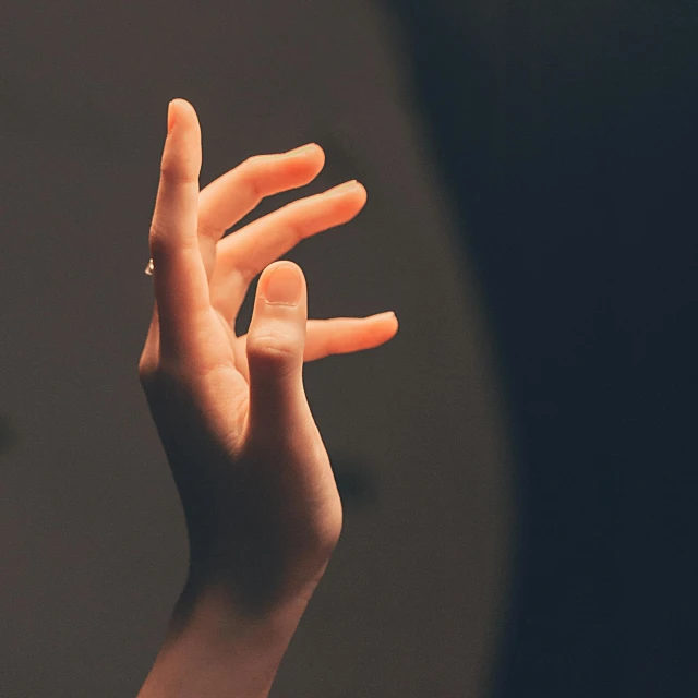 a close up of a person's hand holding something, by Jan Rustem, pexels, realism, dark dance photography aesthetic, plain background, brooke shaden detailed, shrugging