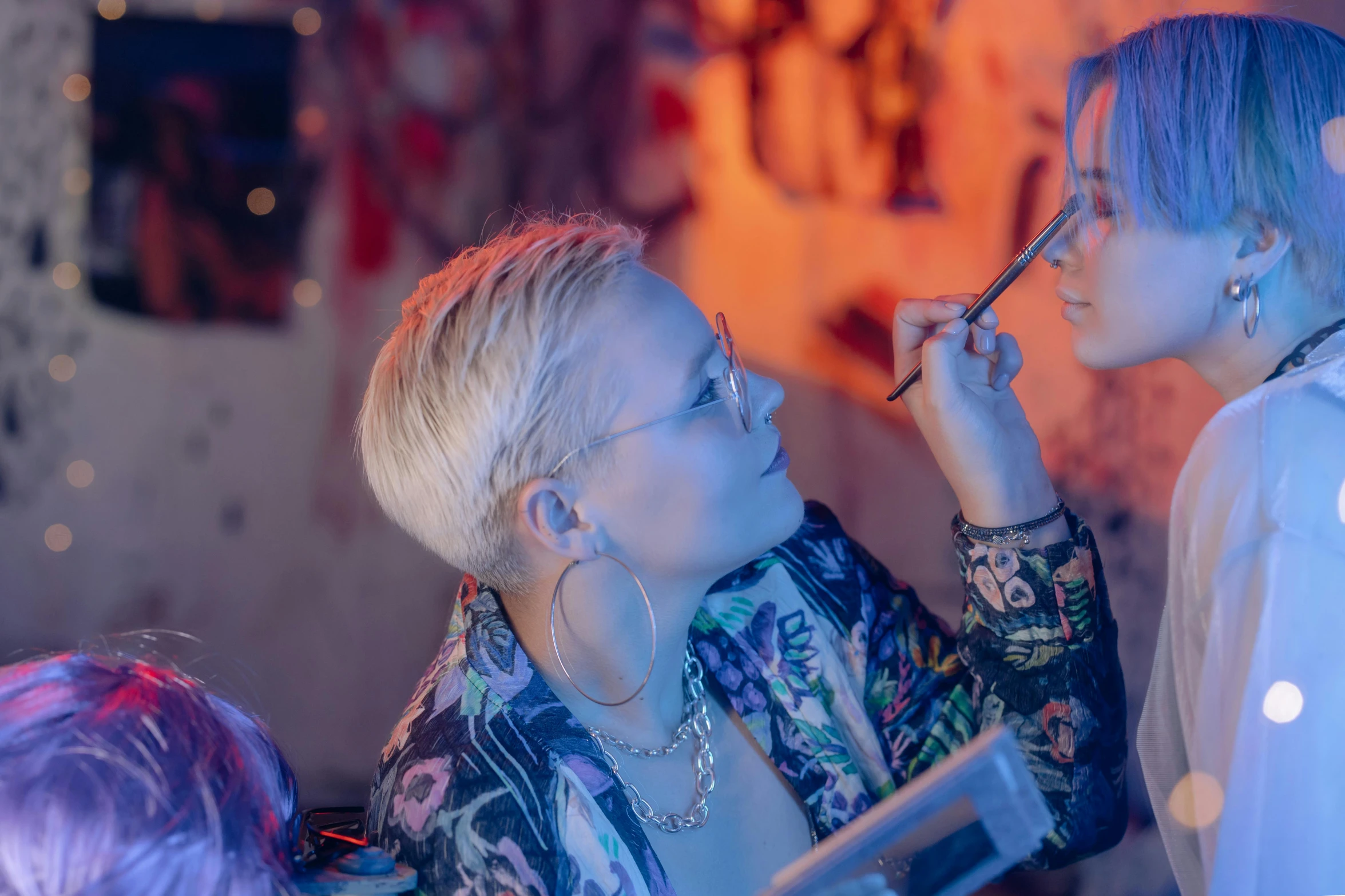 a woman putting makeup on another woman's face, inspired by Elsa Bleda, trending on pexels, process art, girl wearing round glasses, nightlife, girl with short white hair, film still promotional image