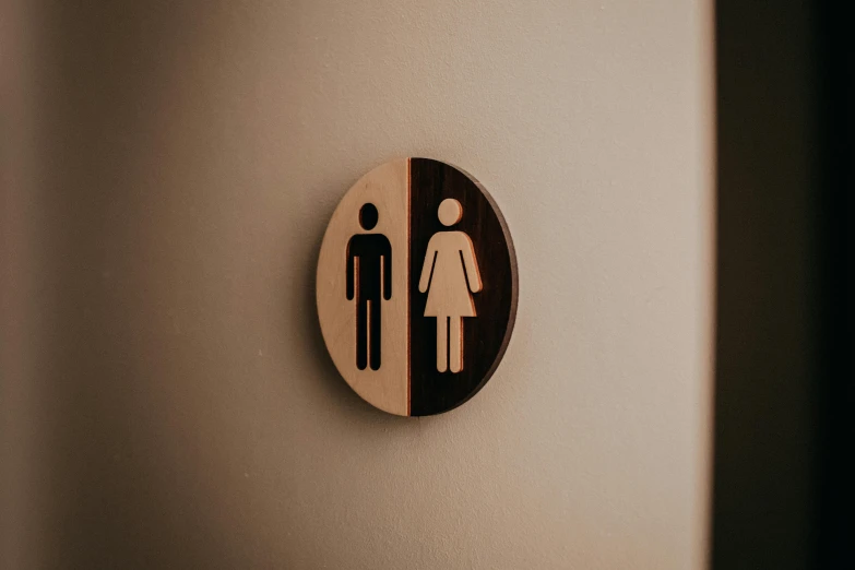 a close up of a toilet sign on a wall, by Julia Pishtar, trending on unsplash, portrait of two people, brown, wooden, circular