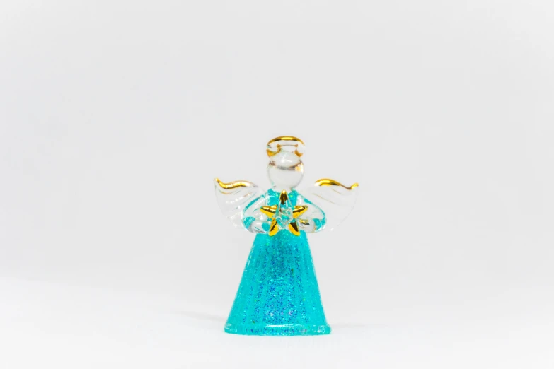 a glass figurine of an angel on a white background, by Joseph Werner, pexels, cyan gold blank light, wearing star filled mage robes, miniature product photo, small