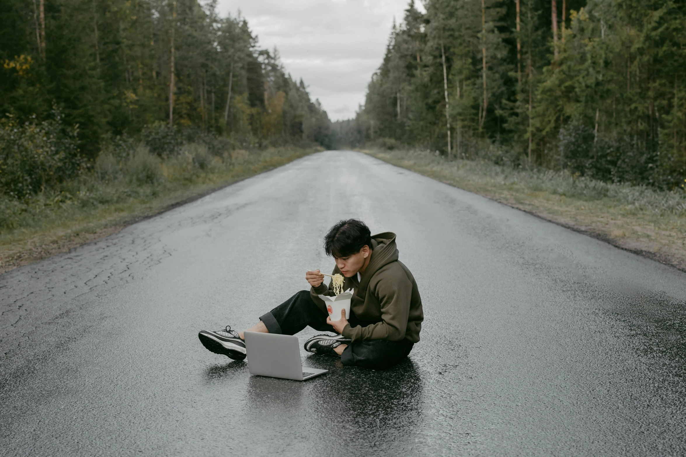 a man sitting on the side of a road with a laptop, by Emma Andijewska, pexels contest winner, having a snack, cai xukun, wet road, jesper esjing