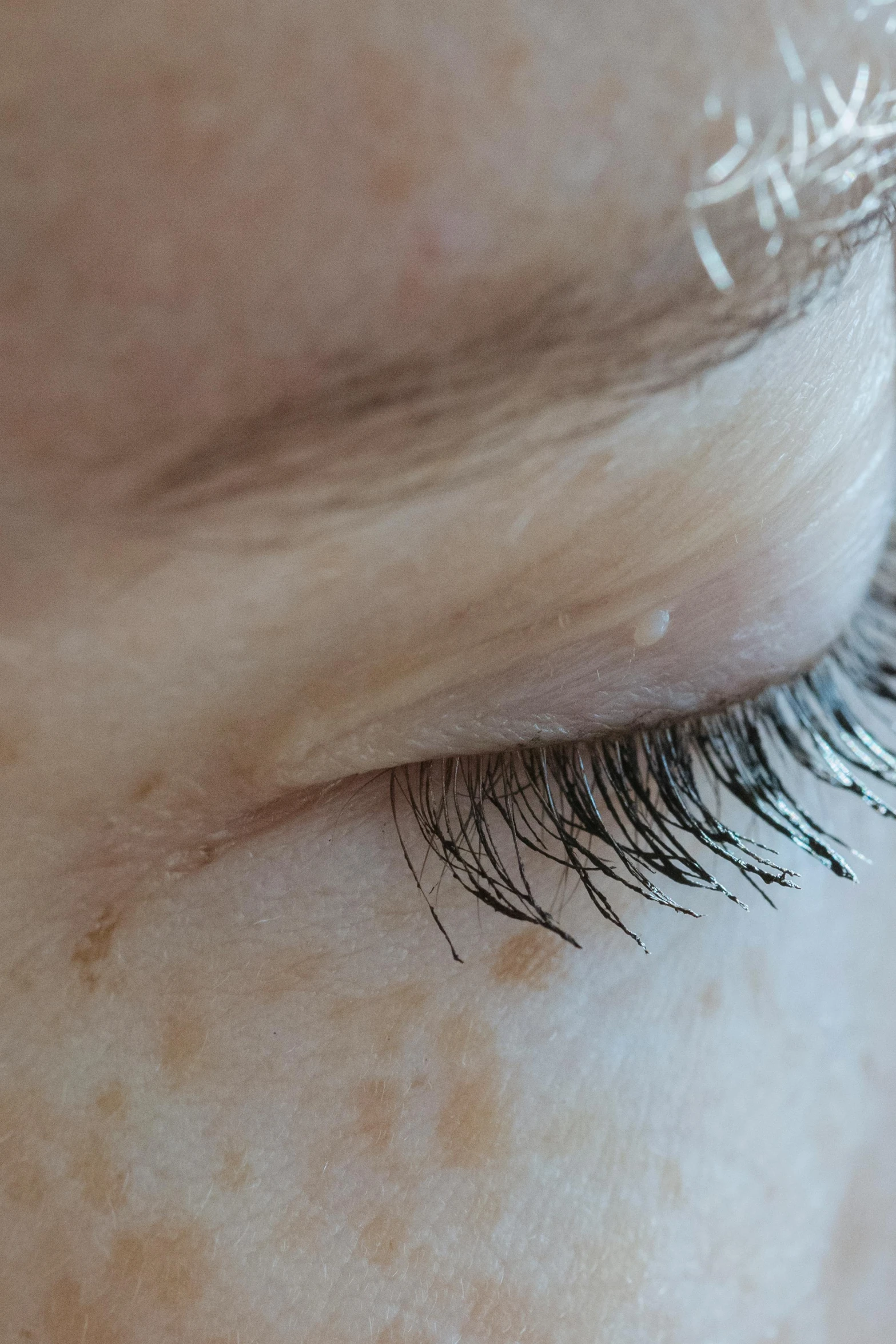 a close up of a person's eye with long eyelashes, a stipple, noticeable tear on the cheek, shy looking down, splash image, sideview