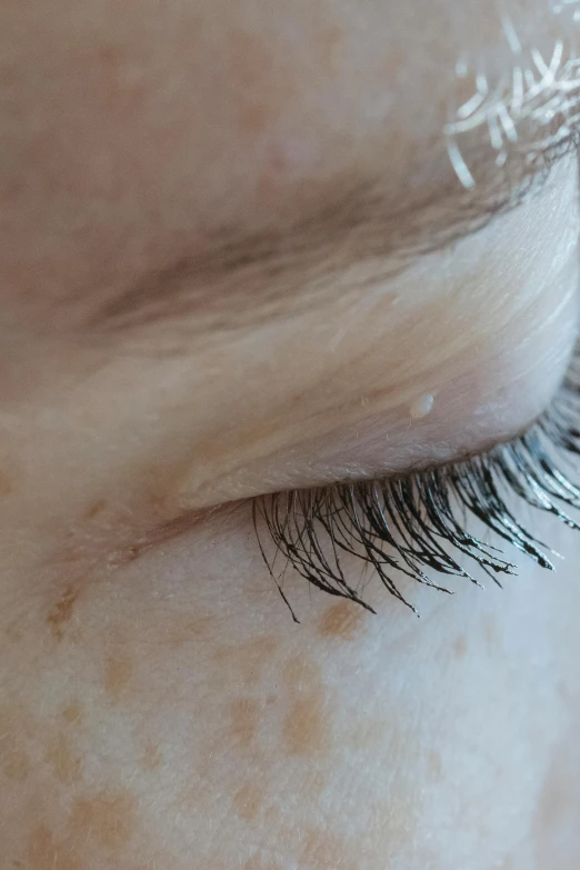 a close up of a person's eye with long eyelashes, a stipple, noticeable tear on the cheek, shy looking down, splash image, sideview