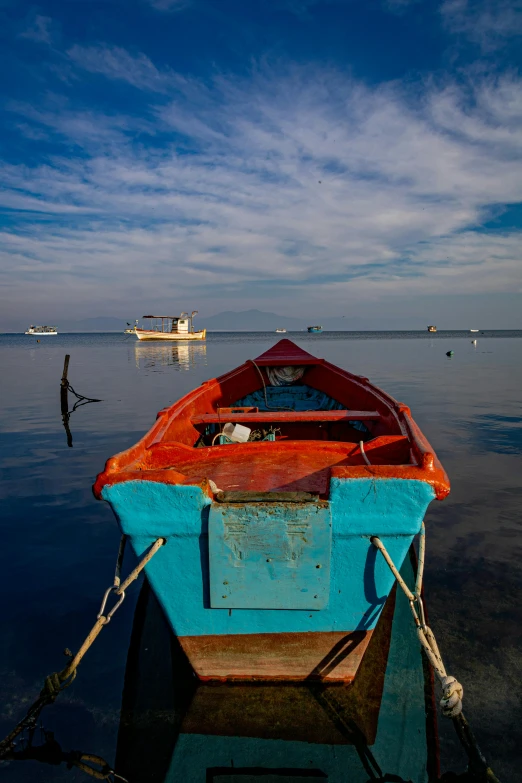 a blue and red boat sitting on top of a body of water, flickr, red sea, ivan bolivian, slide show, in the morning light