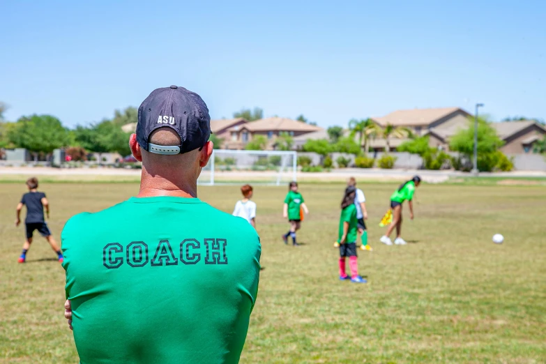 a man in a green shirt watching a soccer game, by Josh Bayer, pexels contest winner, on a green lawn, 5 years old, 1 6 x 1 6, group photo