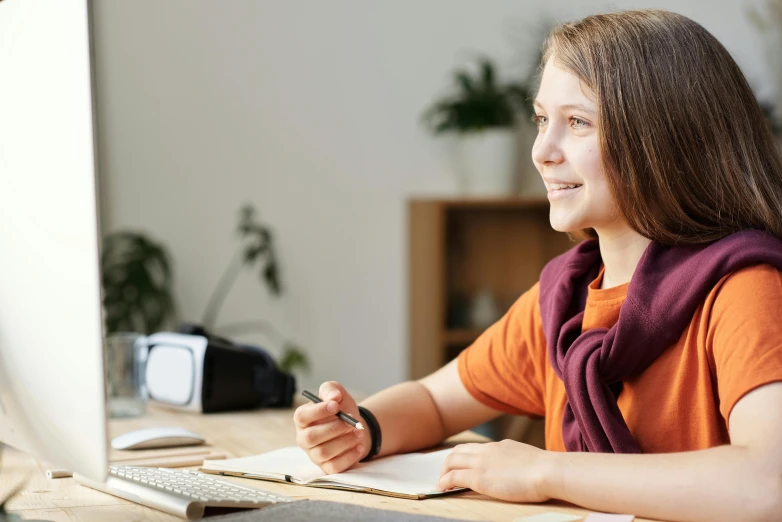a girl sitting at a desk in front of a computer, school curriculum expert, lachlan bailey, tilt and orange, desktop background