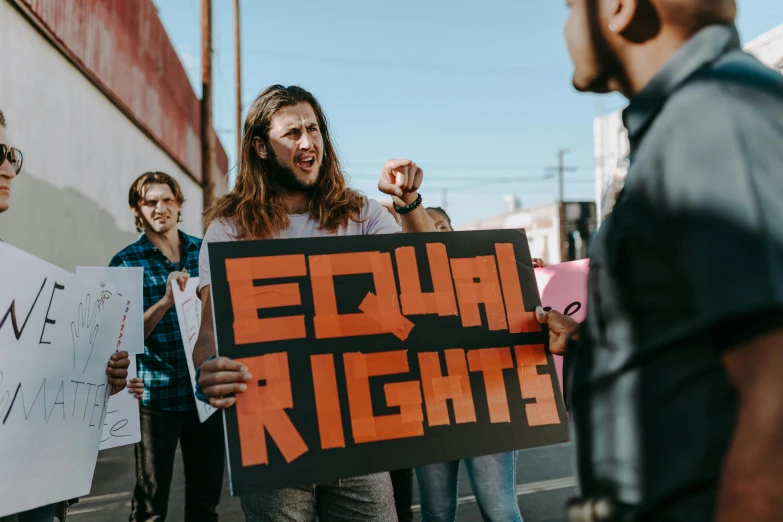 a group of people holding signs in front of a building, trending on pexels, feminist art, knights, man standing, edward robert, bright lights