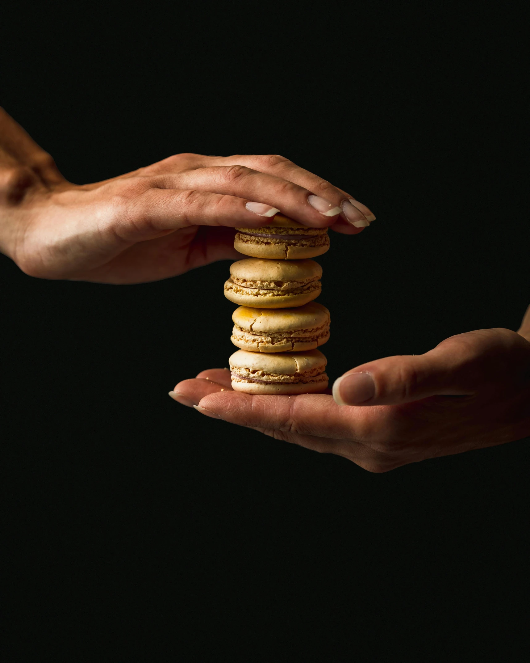 two hands holding a stack of macarons against a black background, unsplash, multiple stories, portait photo, battered, thumbnail