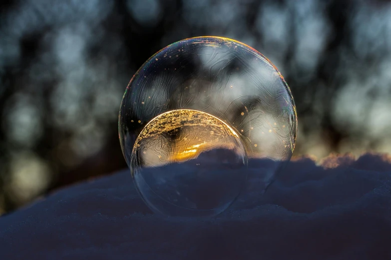 a bubble sitting on top of snow covered ground, by Adam Marczyński, pexels contest winner, evening sunlight, glass bulbs, gold, spherical lens