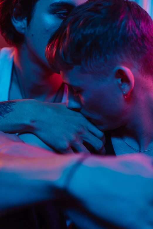 a couple of men standing next to each other, inspired by Nan Goldin, trending on pexels, blue and red tattoo, lesbian embrace, movie still from bladerunner, teenage boy