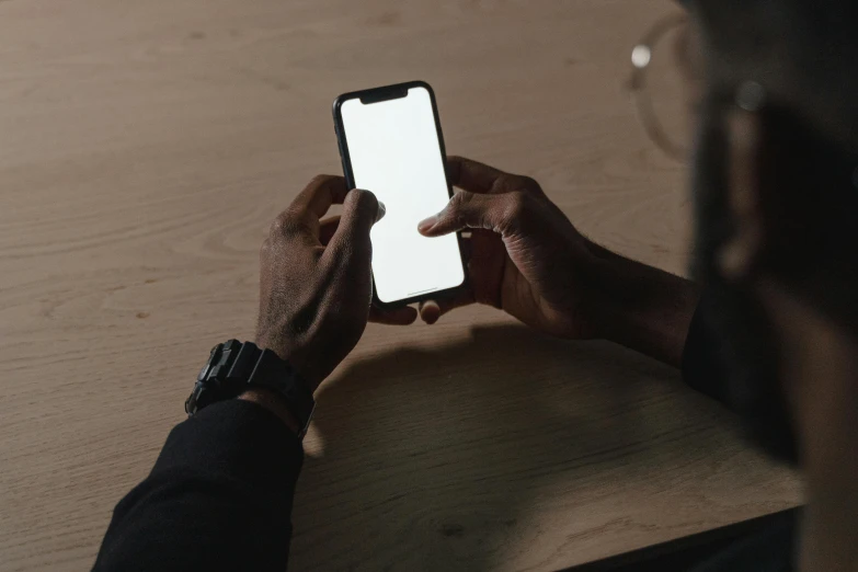 a close up of a person holding a cell phone, trending on pexels, dark skin tone, sitting on the table, creating a thin monolith, no - text no - logo