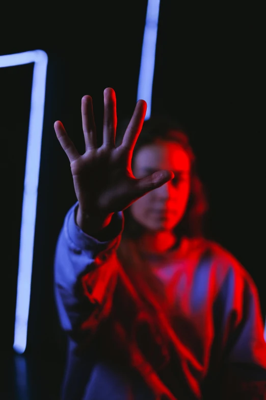 a woman standing in front of a neon sign, pexels, indistinct man with his hand up, abused, standing near a window, red and blue black light