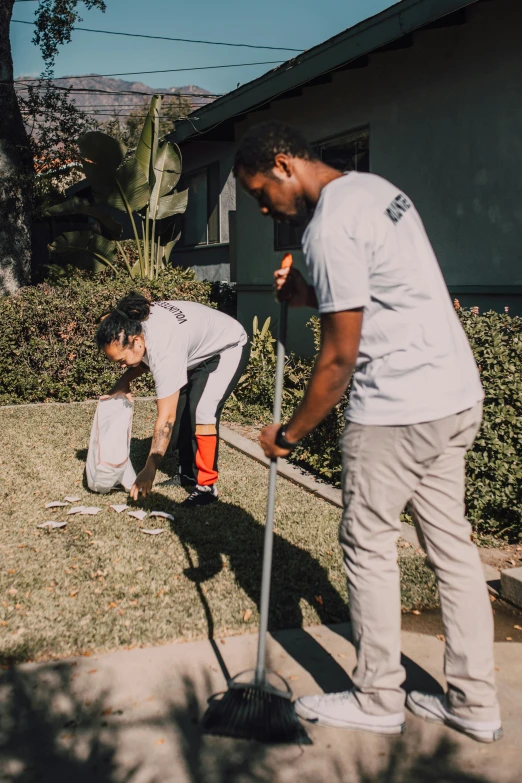 a couple of people that are standing in the grass, using a spade, los angelos, intense line work, standing outside a house