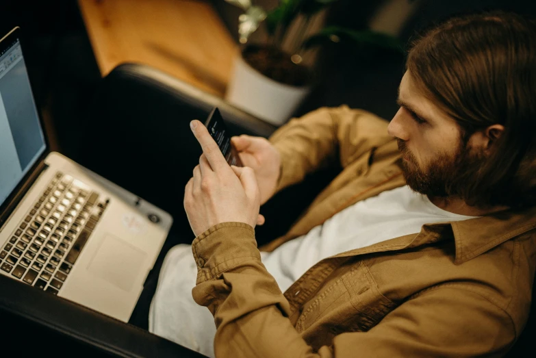 a man sitting in a chair looking at his cell phone, trending on pexels, happening, he is wearing a brown sweater, avatar image, maintenance photo, thumbnail