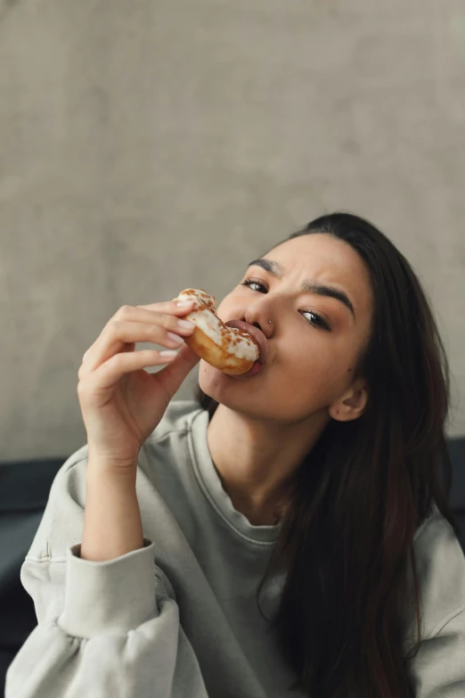 a woman sitting on a couch eating a donut, a portrait, trending on pexels, made of glazed, potato skin, square, high quality picture