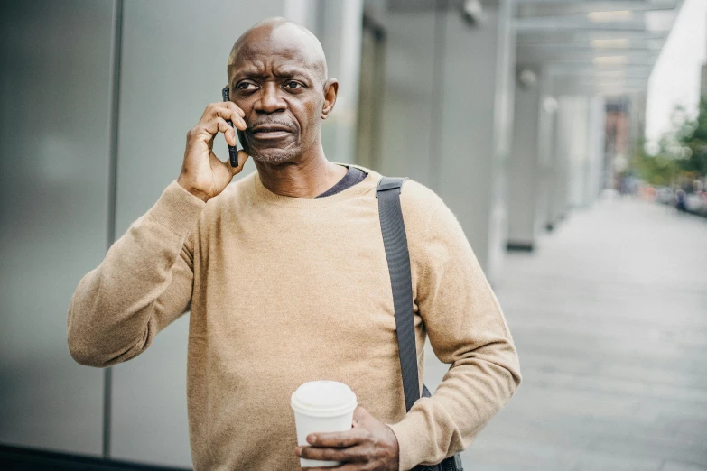 a man talking on a cell phone while holding a cup of coffee, a photo, emmanuel shiru, middle aged man, thumbnail, black. airports