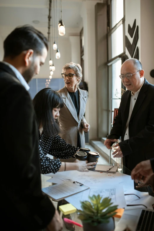 a group of people standing around a table, pexels contest winner, modernism, norman foster, design thinking, wearing a suit and glasses, woman