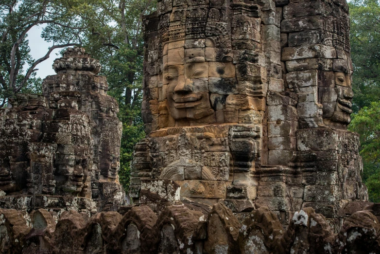 a group of stone statues sitting on top of a lush green field, angkor, avatar image