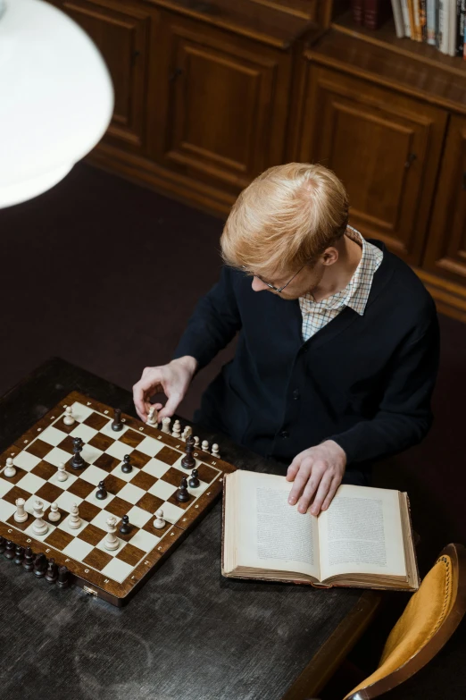 a man sitting at a table playing a game of chess, inspired by George Jamesone, featured on reddit, with book of science, similar to malfoy, ignant, blond