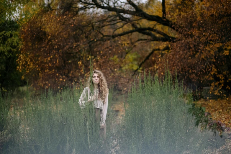 a woman standing in a field of tall grass, a portrait, unsplash, renaissance, portrait image, foliage clothing, in the wood, ground - level medium shot