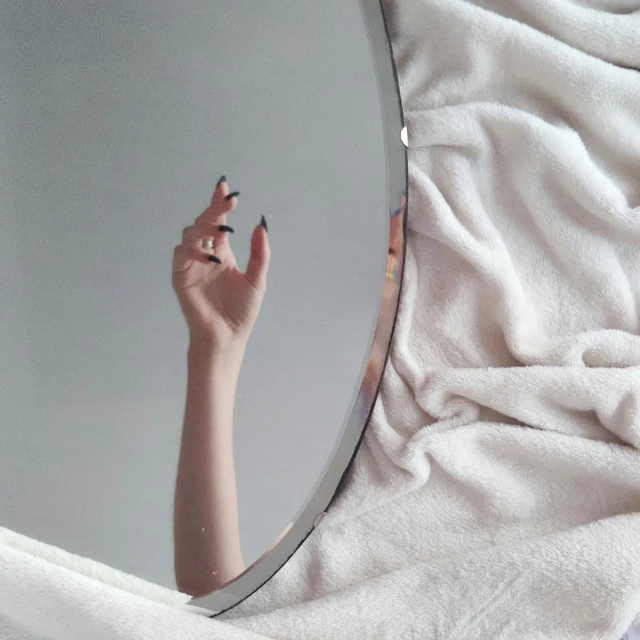 a person holding their hand up in front of a mirror, inspired by Elsa Bleda, aestheticism, white cloth, covered with blanket, pastel goth aesthetic, instagram post