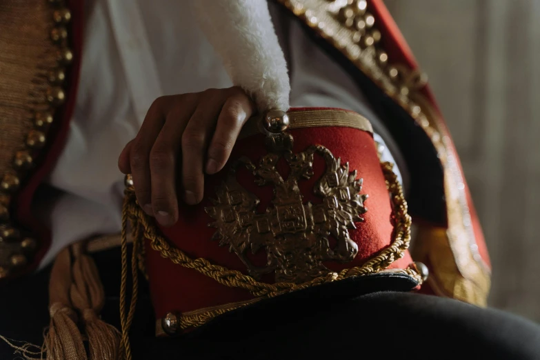 a close up of a person holding a purse, trending on unsplash, qajar art, wearing a red captain's uniform, around the throne, elegant and proud, nordic crown