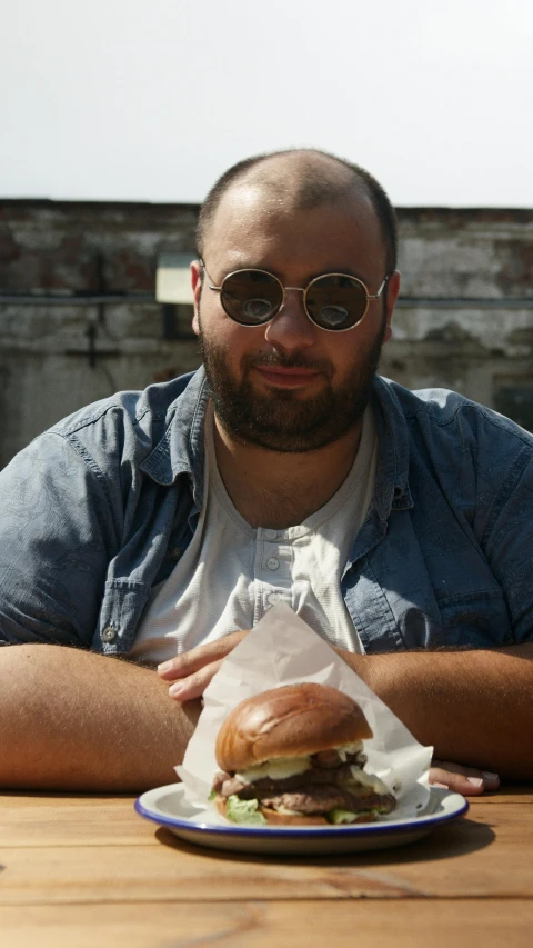 a man sitting at a table with a sandwich in front of him, an album cover, by Matt Cavotta, pexels contest winner, plus-sized, bun, sam nassour, lgbtq