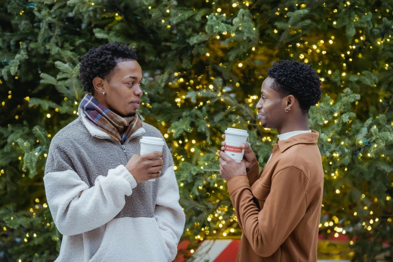 two men standing next to each other in front of a christmas tree, by Carey Morris, pexels, renaissance, coffee cups, ( ( dark skin ) ), al fresco, brown