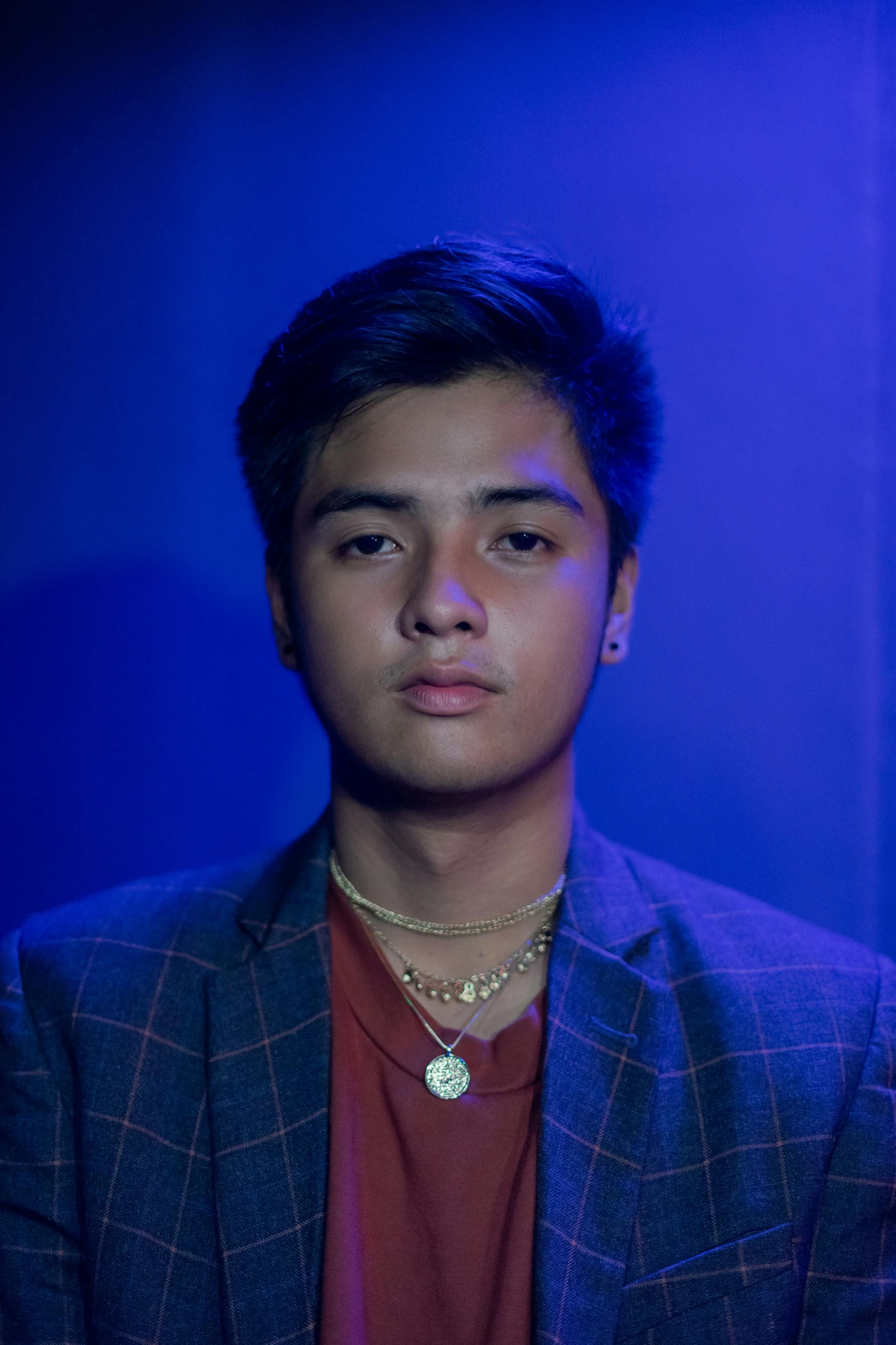 a man standing in front of a blue light, an album cover, inspired by Jorge Jacinto, unsplash, dau-al-set, portrait of jughead jones, runway photo, henry ascensio, serious expression