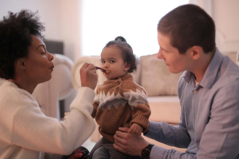 a woman brushing a child's teeth in a living room, pexels contest winner, mix of ethnicities and genders, portrait of family of three, brown and white color scheme, with a stethoscope