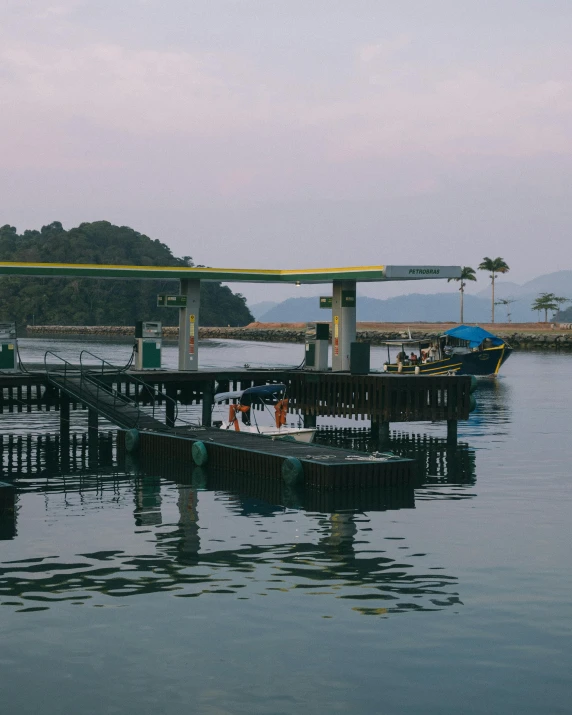 a group of people standing on a dock next to a body of water, pexels contest winner, sumatraism, boat dock, inlets, a photo of the ocean, slight haze