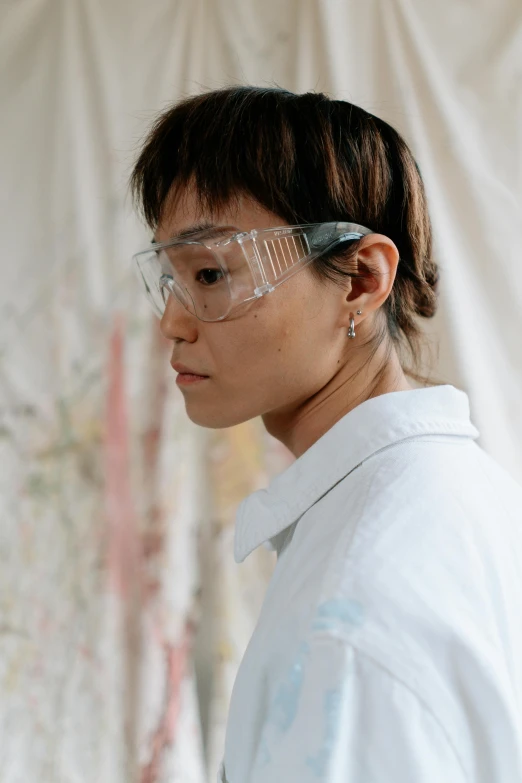a woman in a lab coat and safety glasses, a hyperrealistic painting, inspired by Pan Yuliang, trending on pexels, painted overalls, profile pic, white wall coloured workshop, wearing translucent sheet