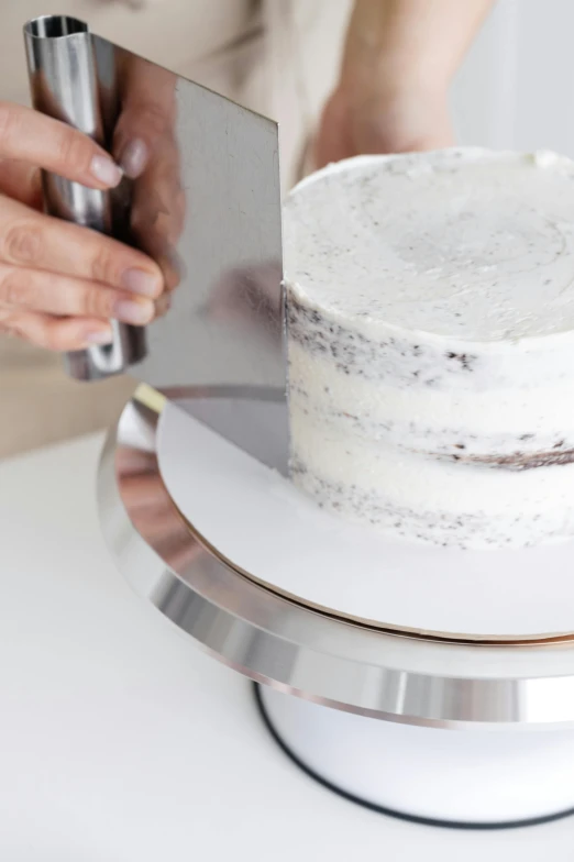 a person cutting a cake with a knife, white and silver, stainless steel, tall, proportional image