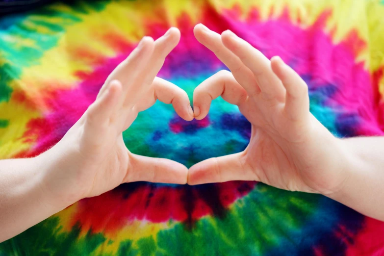 a person making a heart with their hands, inspired by Gabriel Dawe, wearing a tie-dye shirt, avatar image, hippie pad, multi colour