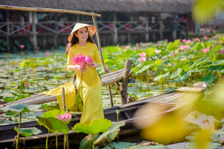 a woman in a yellow dress is sitting on a boat, inspired by Ruth Jên, pexels contest winner, waterlily pond, ao dai, avatar image, wearing pink floral chiton