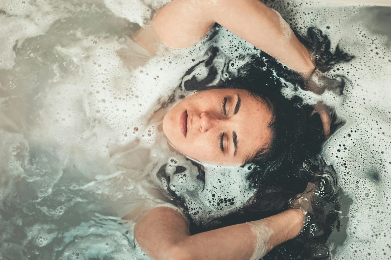 a woman laying in a bathtub with her eyes closed, trending on pexels, process art, ectoplasm, the hair floats on the water, bubbly, teenage girl