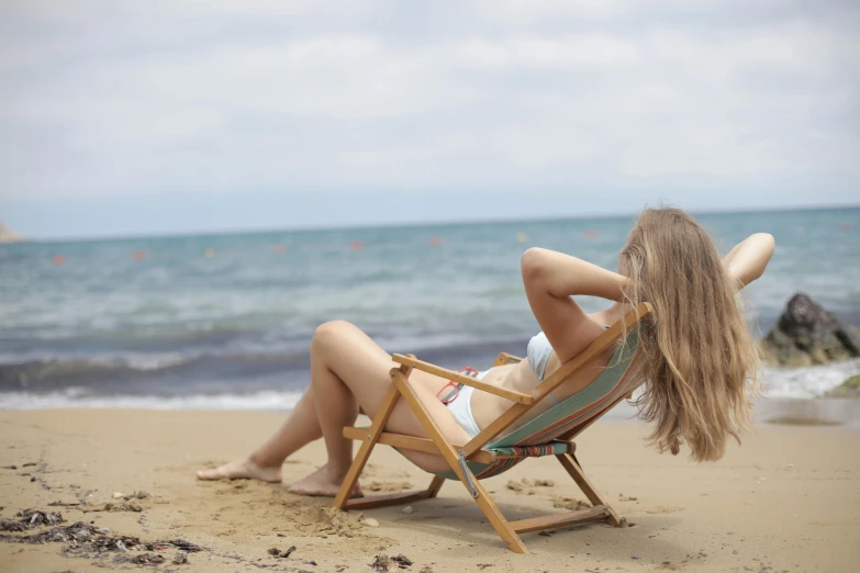 a woman sitting in a chair on a beach, pexels contest winner, renaissance, young blonde woman, tan complexion, profile image, cyprus