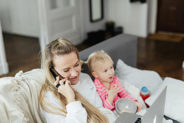 a woman sitting on a couch talking on a cell phone next to a baby, pexels contest winner, working in a call center, kirsi salonen, having a snack, ellie victoria gale