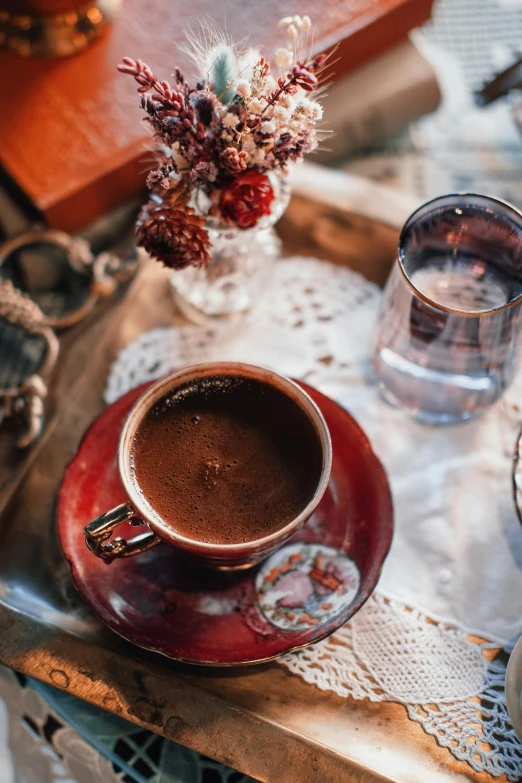 a cup of coffee sitting on top of a wooden tray, a still life, inspired by Elsa Bleda, pexels contest winner, hurufiyya, red and brown color scheme, turkey, place setting, sitting on a mocha-colored table