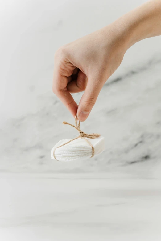 a person tying a string to a glass ornament, a marble sculpture, by Eden Box, trending on pexels, gum tissue, white cloud, packaging, minimal design