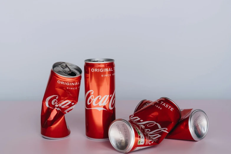 a group of coca cans sitting on top of a table, trending on unsplash, hyperrealism, metallic red, fan favorite, product introduction photo