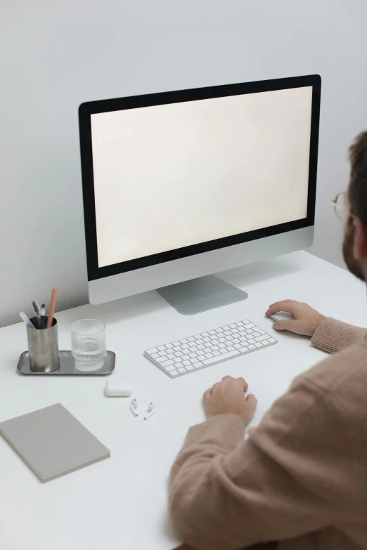 a man sitting at a desk in front of a computer, a computer rendering, trending on pexels, all white render, simple aesthetic, glowing screen, plain background