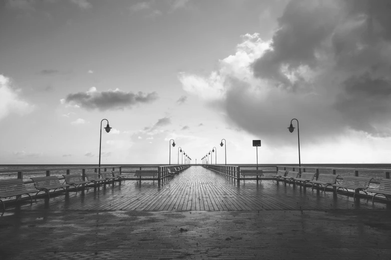 a black and white photo of a pier, by Karl Buesgen, unsplash contest winner, just after rain, vanishing point, light and clouds, empty streets