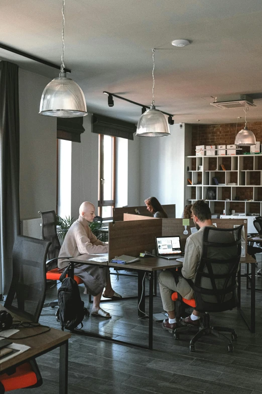 a group of people sitting at desks working on laptops, unsplash, renaissance, man sitting facing away, low quality photo, interior of a loft, caucasian