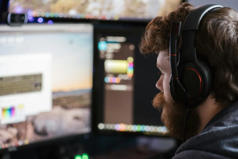 a man wearing headphones sitting in front of two monitors, trending on pexels, indie games, instagram post, close up to the screen, nvidia promotional image