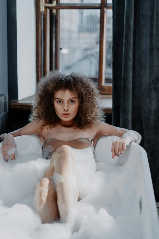 a woman sitting in a bathtub filled with foam, inspired by Leonor Fini, trending on pexels, renaissance, fair curly hair, sitting in a lounge, angelina stroganova, at a fashion shoot