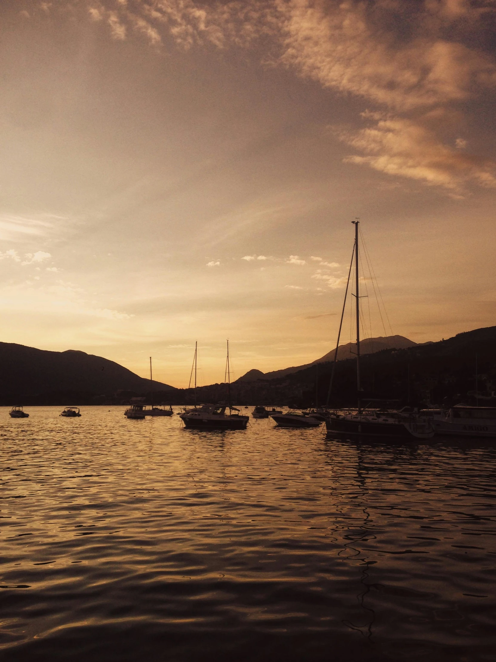 a group of boats floating on top of a body of water, a picture, inspired by Matteo Pérez, pexels contest winner, dappled golden sunset, mountains and sunset!!, 4 k cinematic panoramic view, harbour