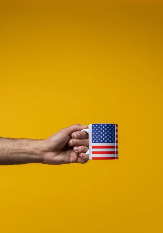 a person holding a coffee cup with an american flag on it, by Andrew Domachowski, colors: yellow, usa-sep 20, album, programming