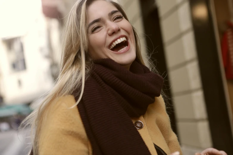 a woman laughing while holding a cell phone, pexels contest winner, scarf, brown, blonde, gif