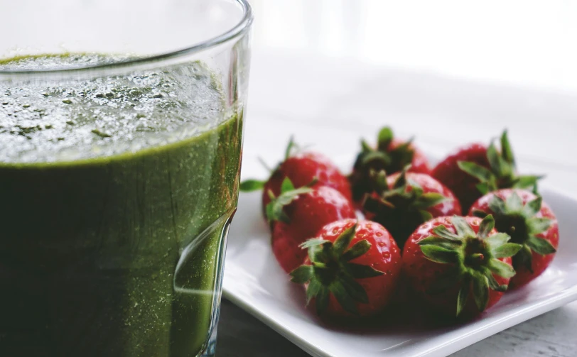 a glass of green juice next to a plate of strawberries, pixabay, waking up, background image, unedited, body shot